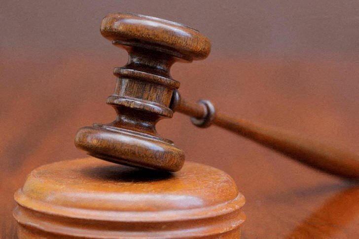 A wooden gavel sits on top of a round, wooden sound block