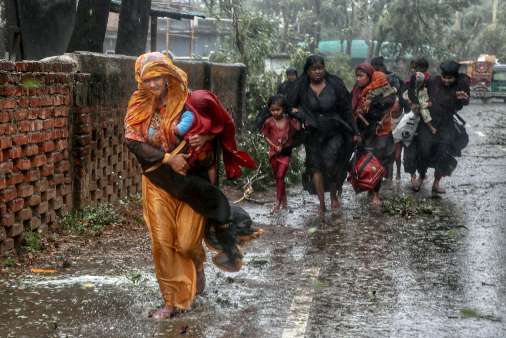 People walk through a downpour on flooded roads