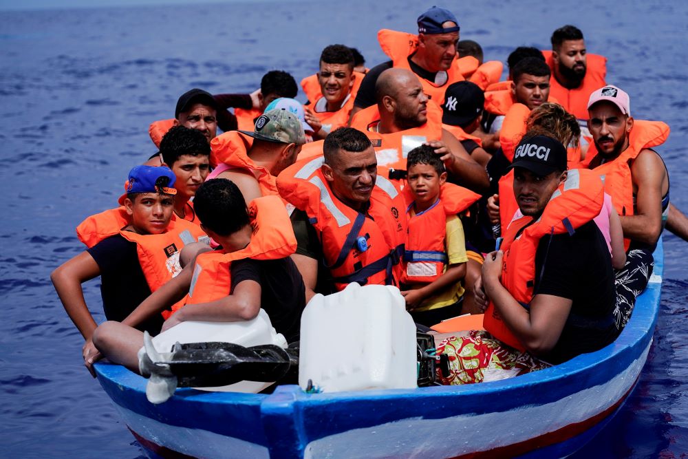 Migrants on a wooden boat wait for the Italian Guardia Costiera near the island of Lampedusa, in the Mediterranean Sea, Sept. 1, 2021.