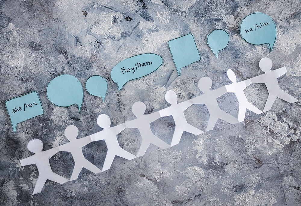 Paper cutout figures with speech bubbles saying their pronouns (Dreamstime/Faithiecannoise)