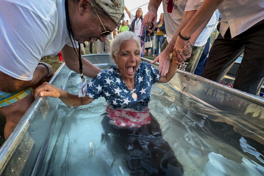 A woman is baptized during the ReAwaken America Tour at Cornerstone Church in Batavia, New York, on Aug. 12, 2022. In the version of America laid out at the ReAwaken tour, Christianity is at the center of American life and institutions, it's under attack, and attendees need to fight to restore and protect the nation's Christian roots. (AP/Carolyn Kaster)