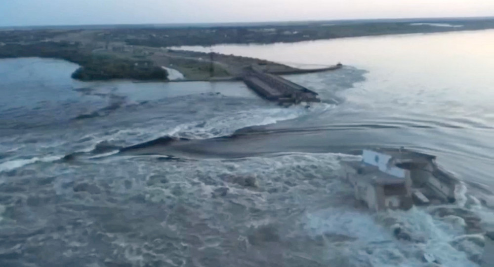 Water flows over banks and between two broken parts of a concrete dam