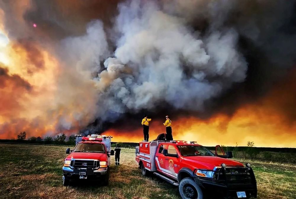 Firefighters stand on a Kamloops Fire Rescue truck at a wildfire near Fort St. John, British Columbia, May 14, 2023. Wildfires have always occurred, but experts say the warming climate is increasing their severity. (OSV News photo/Kamloops Fire Rescue handout via Reuters)