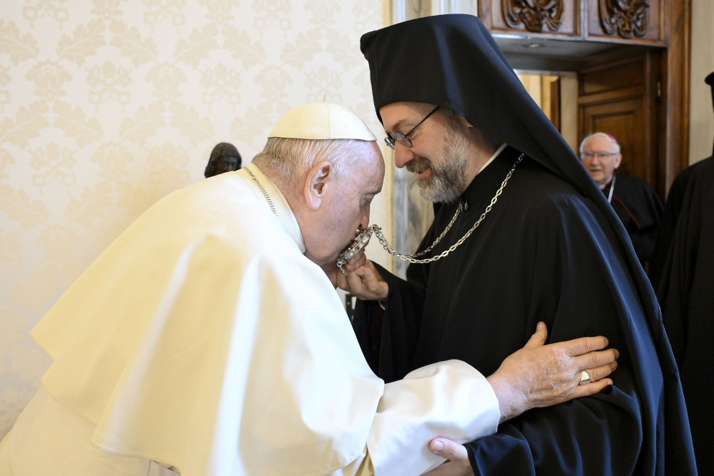 Pope Francis kisses an Orthodox leaders necklace while embracing the leader's arm