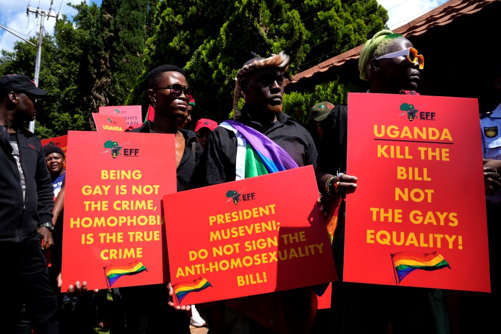 People hold signs supporting lgbtq rights in Uganda.