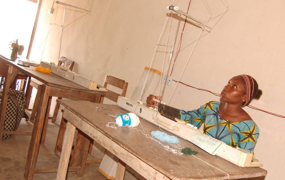 Anita Nyamdio looks at the knitting machine hanger to ensure accuracy at the Women's Empowerment Center, run by Sisters, Home Visitors of Mary, in Gboko Diocese of Nigeria. (GSR photo/Valentine Benjamin)