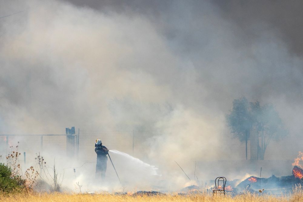 A firefighter tries to extinguish a fire, as a wildfire burns in the village of Kiotari, on the island of Rhodes, Greece, July 24, 2023. (OSV News/Reuters/Lefteris Damianidis)