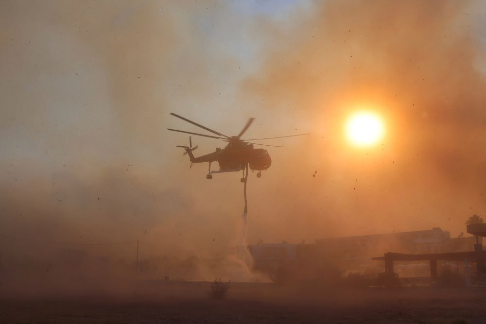 A firefighting helicopter fills water from a pool, as a wildfire burns in the village of Gennadi, on the island of Rhodes, Greece, July 25, 2023. (OSV News/Reuters/Nicolas Economou)