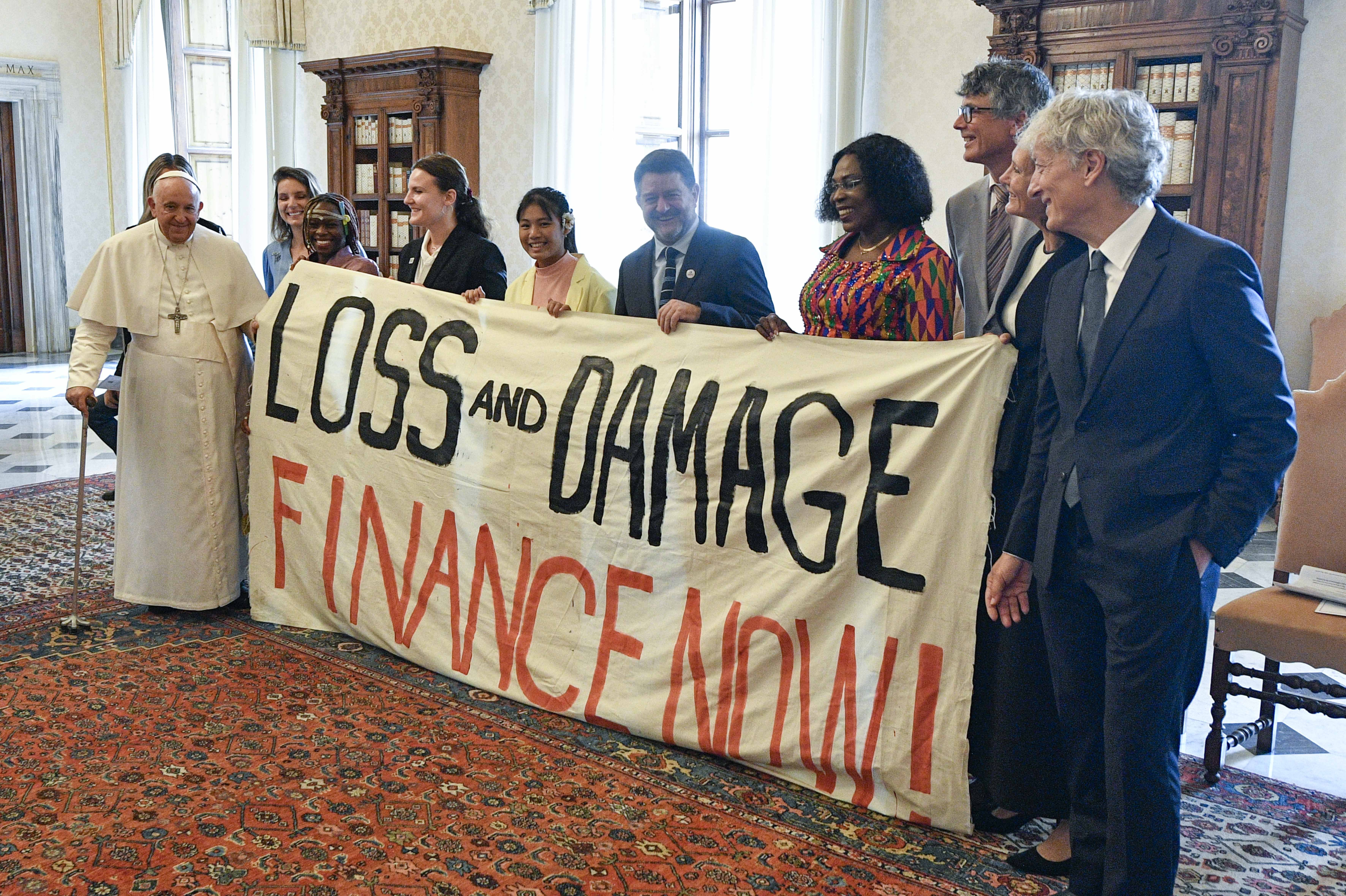 Pope Francis joins others in holding a banner during an audience at the Vatican June 5, 2023, with the organizers of the Green & Blue Festival. The banner calls for financing a "loss and damage" fund that was agreed upon at the COP27 U.N. climate conference in 2022. The fund would seek to provide financial assistance to nations most vulnerable and impacted by the effects of climate change. (CNS photo/Vatican Media)