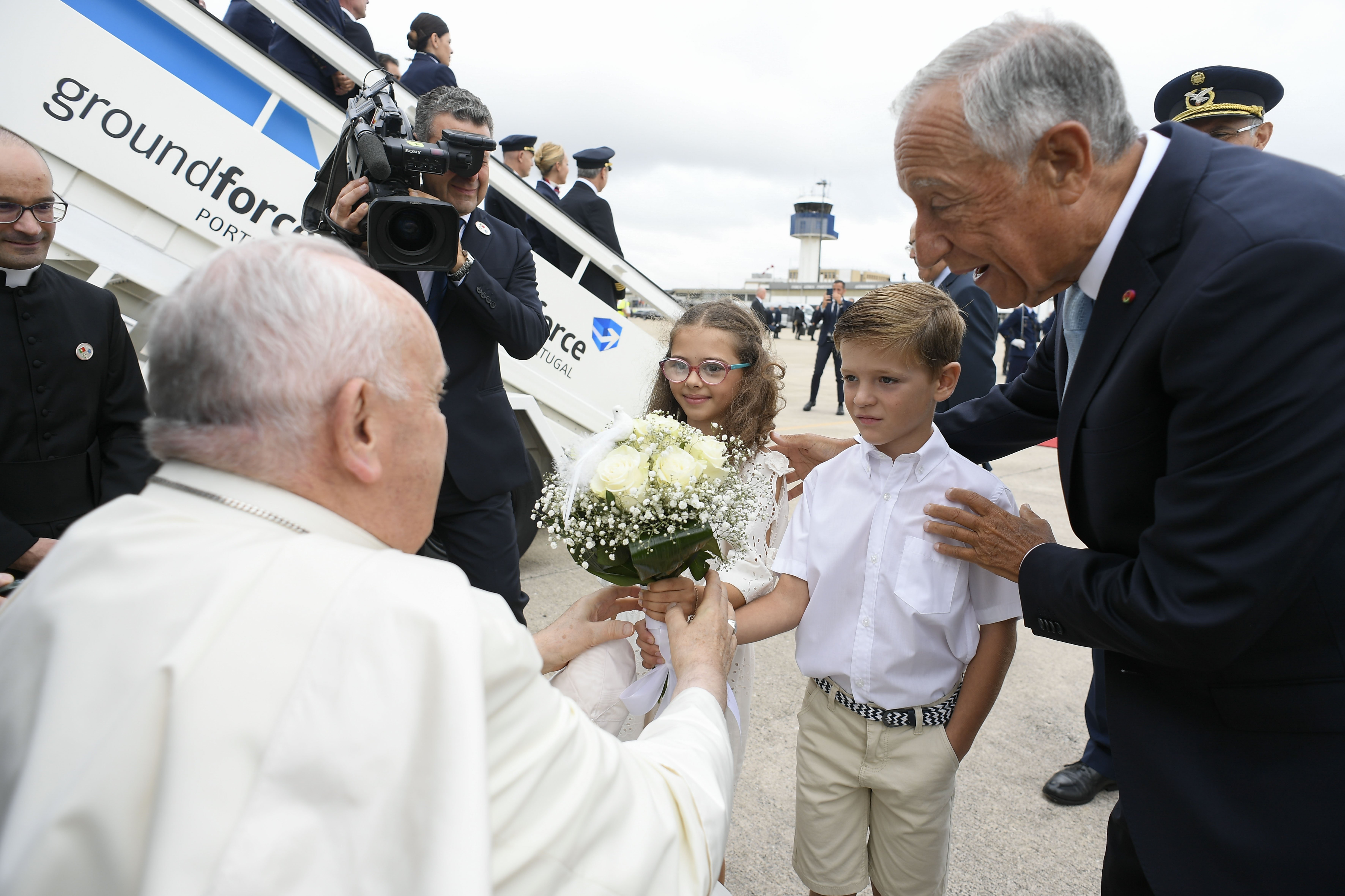 Portuguese President Marcelo Rebelo de Sousa and children carrying flowers greet Pope Francis upon his arrival at Figo Maduro Air Base in Lisbon Aug. 2, 2023. The pope began a five-day trip to Portugal to participate in World Youth Day. (CNS photo/Vatican Media)