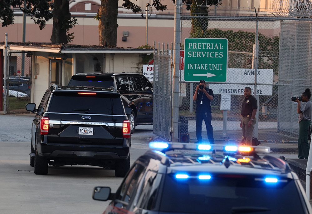 Former U.S. President Donald Trump arrives to turn himself in to be processed at Fulton County Jail in Atlanta after his Georgia indictment, Aug. 24. Trump is one of 19 defendants in the indictment that alleges racketeering by a criminal organization that tried to overturn the election results. Local authorities said Trump would be treated like any other defendant. (OSV News/Reuters/Brendan McDermid)