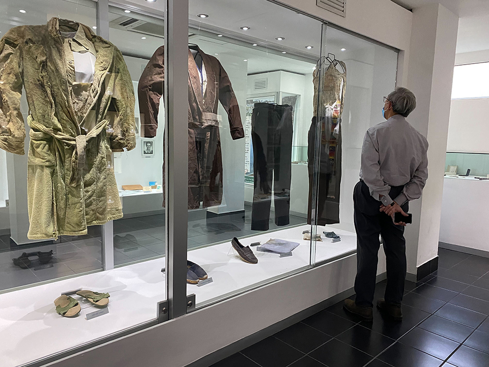 A bishop at the Centro Romero in San Salvador on Jan. 18, 2022, looks at a display of clothes the Jesuits and their housekeepers were wearing when they were murdered in 1989. (NCR photo/Rhina Guidos)