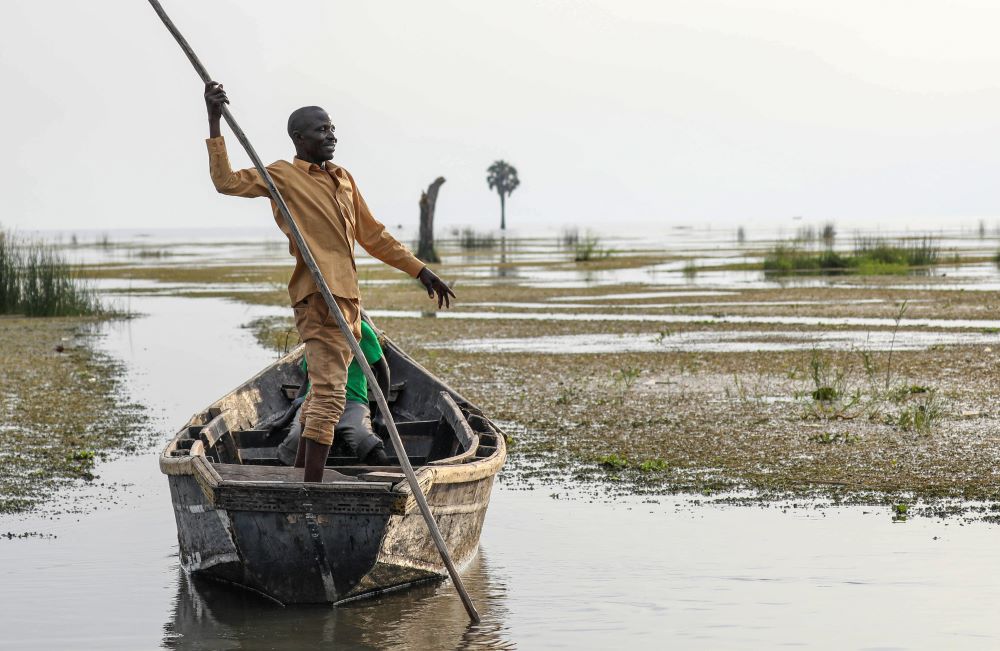 John Gafabusa, custodian of the Mutyona natural sacred site near Buliisa, Uganda, points at a water covered sacred site on Lake Albert at the Karakaba landing site, Aug. 3, 2023.