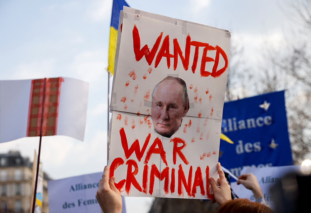 A person near the Place de la Republique in Paris holds a placard with an image of Russian President Vladimir Putin during an anti-war protest March 5, 2022, following Russia's invasion of Ukraine. (OSV News/Reuters/Johanna Geron)