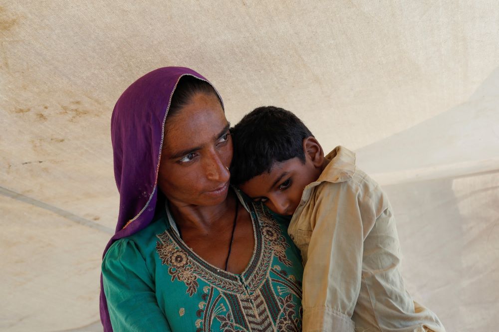 A woman who became displaced following rains and floods during the monsoon season holds her child while standing outside her tent in Sehwan, Pakistan, Sept. 13, 2022. (OSV News/Reuters/Akhtar Soomro)