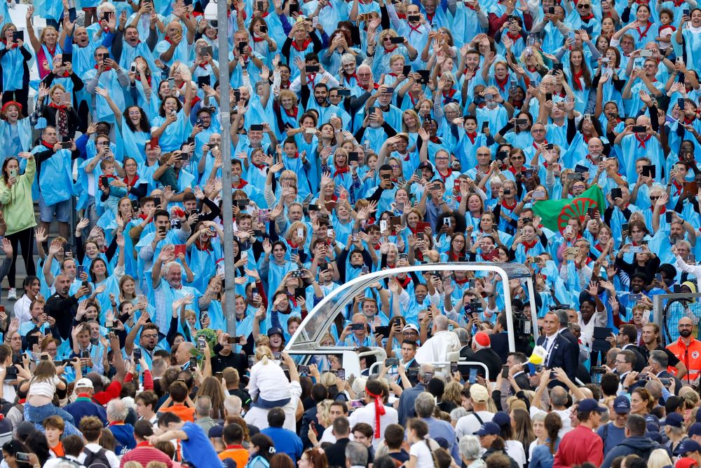 Large crowd in stadium cheers as pope rides popemobile.