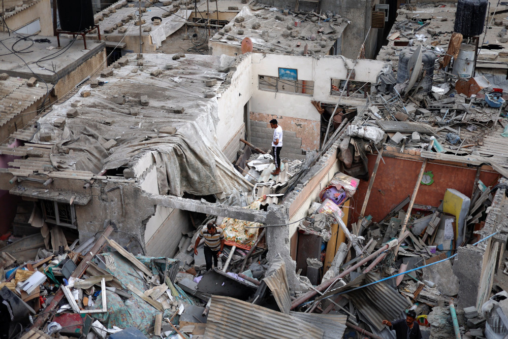 A person stands on the top of rubble from destroyed buildings