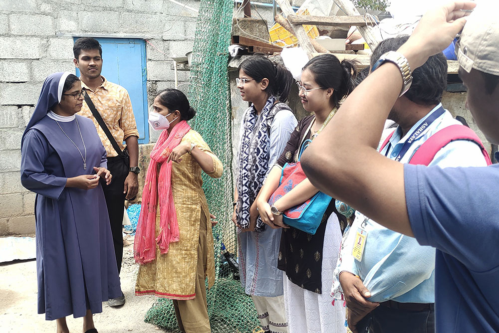 Poor Handmaids of Jesus Christ Sr. Bindu Jose interacts with students of social work from Christ College at the labor camp in Jyothinagar in Bengaluru, southern India. (GSR photo/Thomas Scaria)