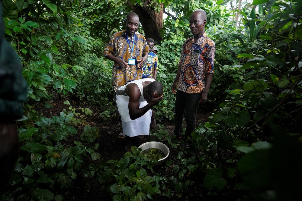 A voodoo worshiper washes his face after visiting the Bohouezoun sacred forest in Benin, on Thursday, Oct. 5, 2023. As the government grapples with preserving the forests while developing the country, Voodoo worshippers worry the loss of its spaces could have far reaching effects. (AP/Sunday Alamba)