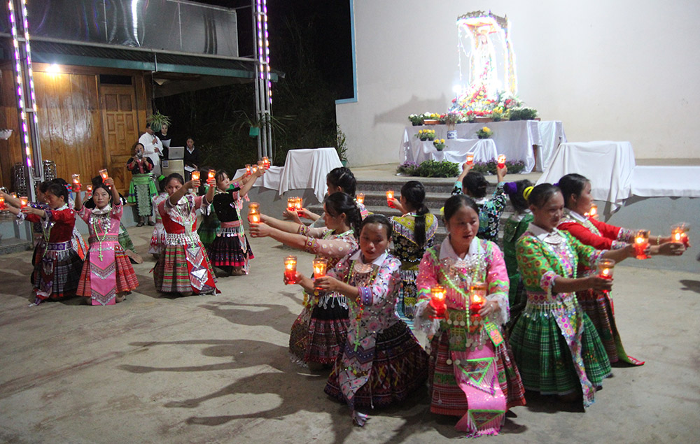 Eighteen Hmong women in costumes dance with candles in front of a Marian statue decorated with flowers at Sung Do Church in Vietnam Oct. 7. (GSR photo/Joachim Pham)