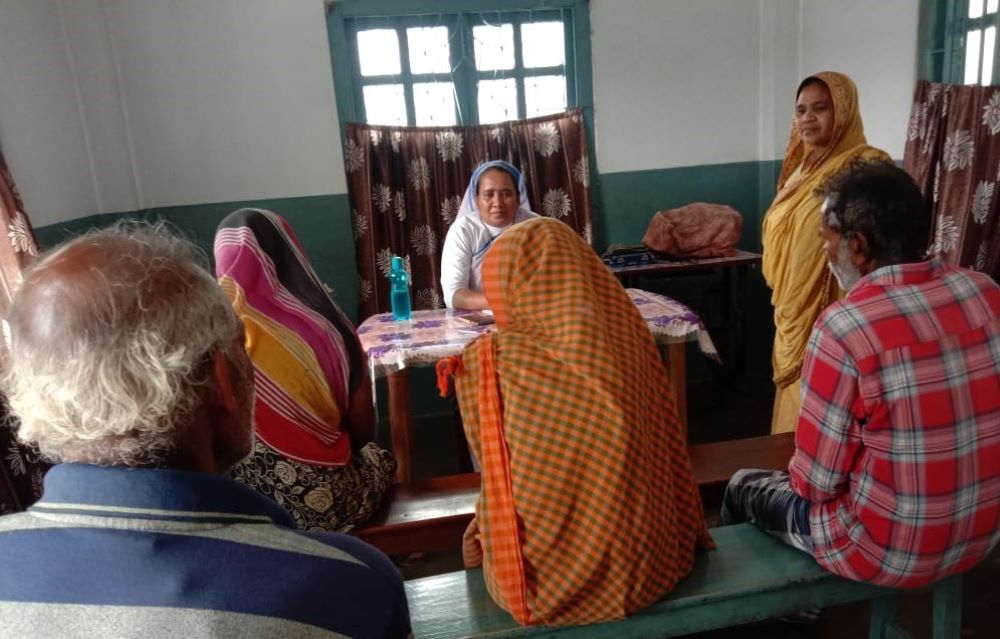 A nun sits in front of a group of people and talks. 