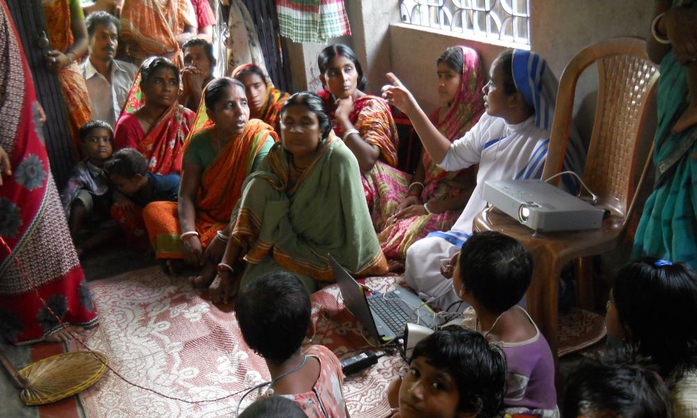 A nun sits among a group of women, talking.