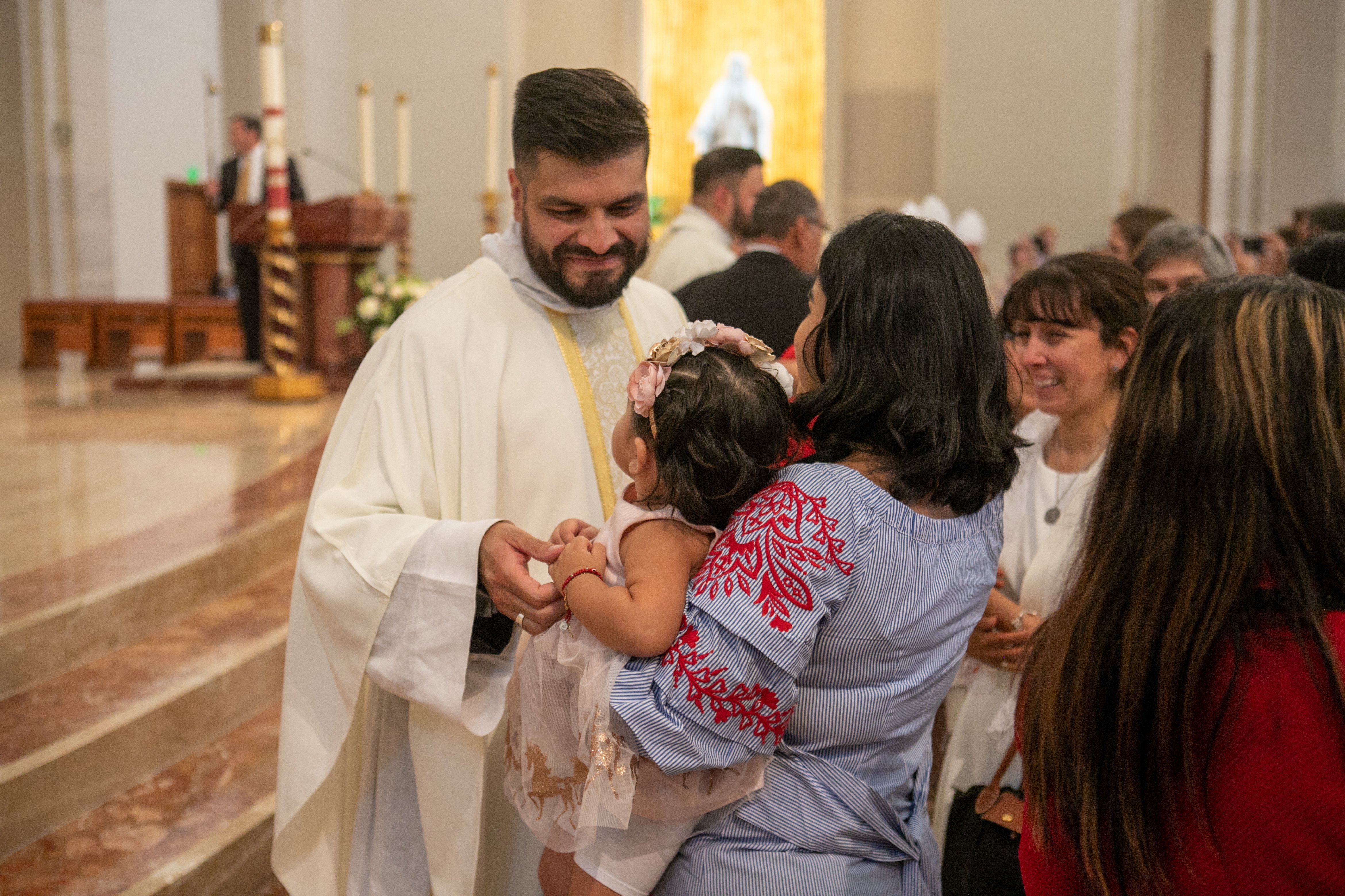 Father Luis Garcia is seen greeting a parishioner and her toddler in Houston June 4, 2022. (OSV News photo/James Ramos, Texas Catholic Herald)