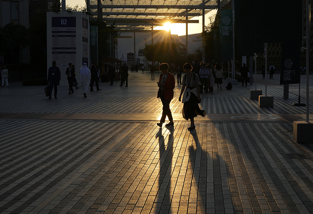 People walk through the COP28 U.N. climate summit, Tuesday, Dec. 5, in Dubai, United Arab Emirates. Catholic institutions wrote in a letter issued Dec. 5 to the president of the COP28 climate change summit that nations meeting in Dubai should adopt a new treaty charting the end of fossil fuel use. (AP photo/Rafiq Maqbool)