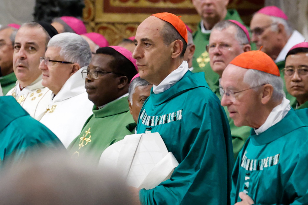 Men wearing green or white vestments wear red or violet zucchettos while facing forward