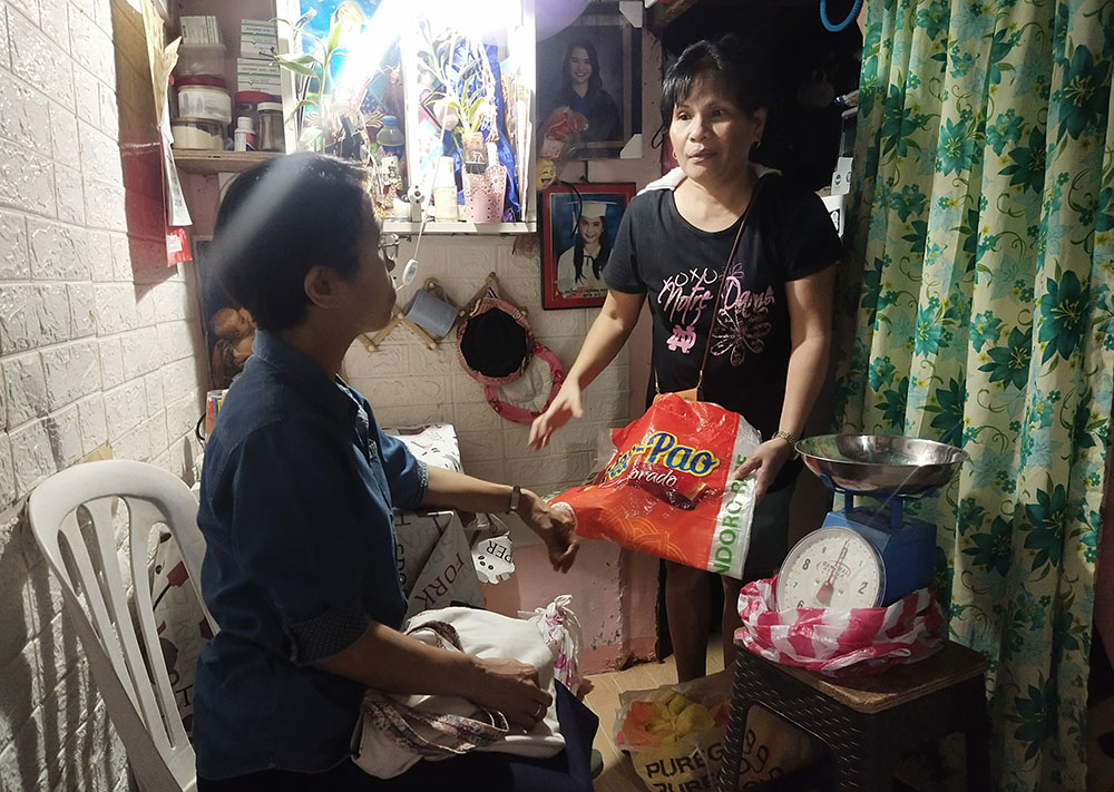 On Sept. 2, 2023, in Paco, Manila, Philippines, Sister Arabella and Recy discuss the progress of Recy's income-generating project in her small house, which is also the place where she sells her rice. (Jerahmeel Cruz)