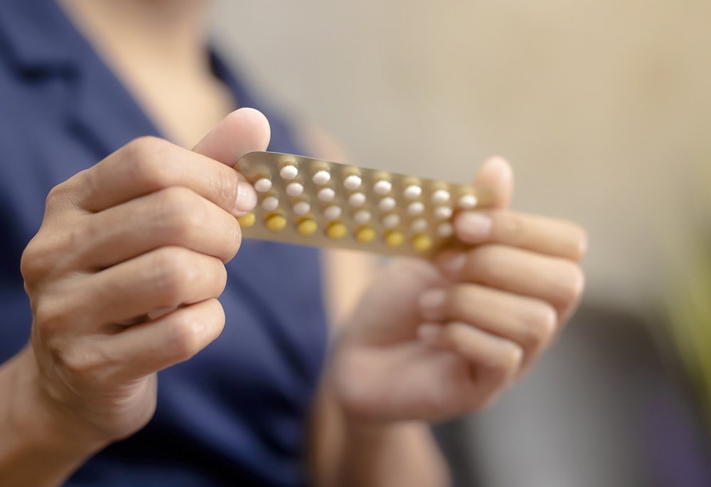 Woman holding a blister pack of birth control pills (Dreamstime/Patcharin Simalhek)