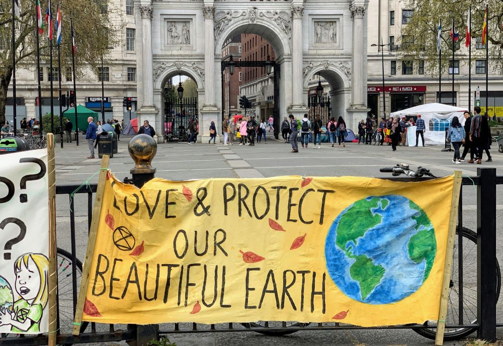 banner hangs on fence: "Love and protect our beautiful earth"