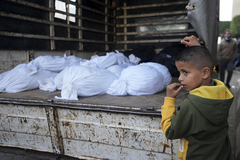 A Palestinian boy stands by the bodies of relatives killed in the Israeli bombardments of the Gaza Strip in front of the morgue of the Al Aqsa Hospital in Deir al Balah Feb. 24. (AP/Adel Hana)