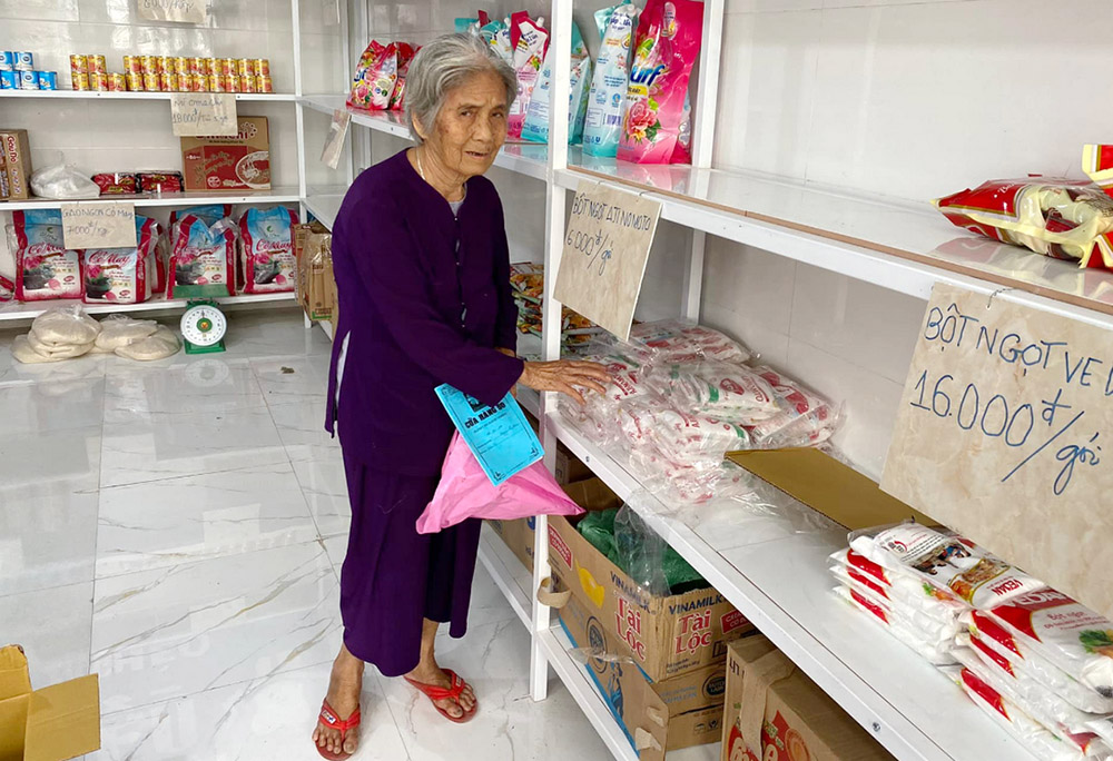 Tran Thi Lan, 82, who lives alone on a small boat in a river in Thua Thien Hue province, "buys" basic food at a zero-dong shop run by St. Paul de Chartres sisters. Sr. Mary Tran Thi Hoan said Lan is among 100 elderly people, scrap collectors, street vendors, porters, motorbike taxi drivers and lottery ticket sellers who are given tokens, 500,000 dong (US$21) each, to "buy" rice, fish sauce, milk, instant noodles, cakes, sweets, tea, cooking oil and other items. (Joachim Pham)