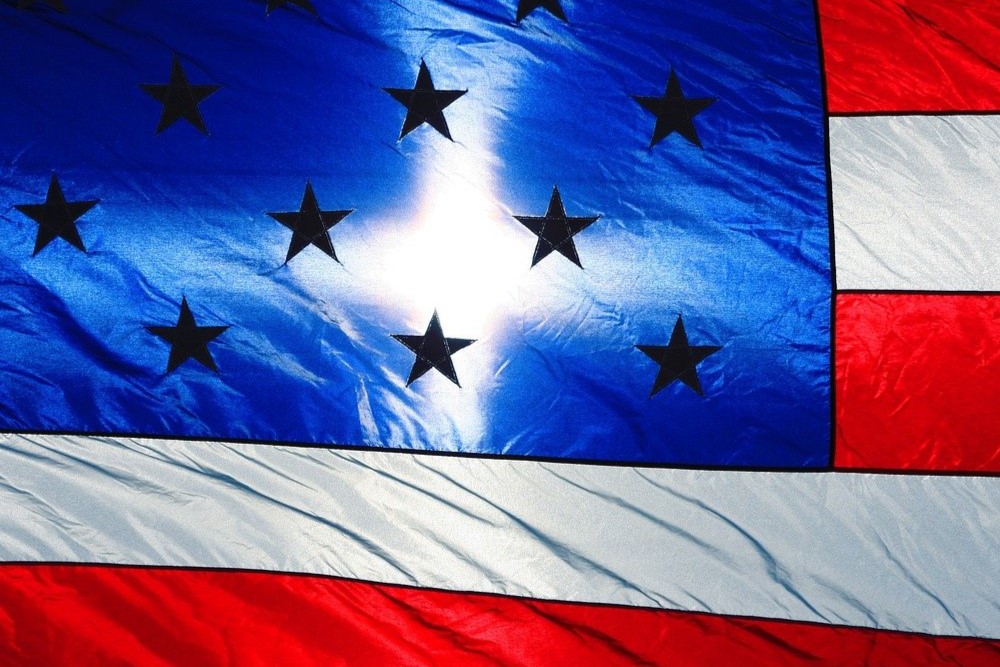 United States flag back-lit by shining cross. 