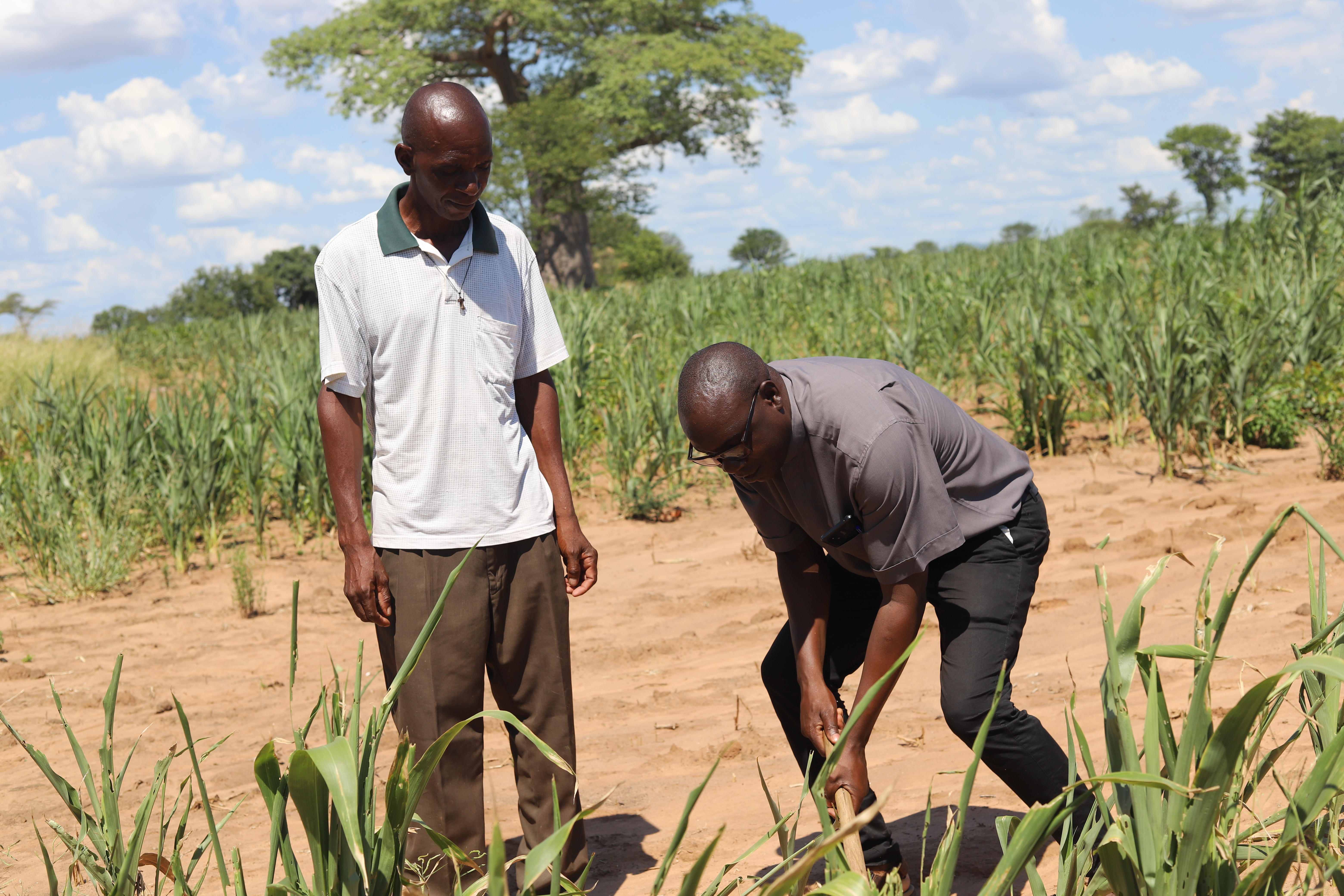 Fr. Christopher Dabu demonstrates to Highly Hangoma the importance of planting trees to restore degraded land.