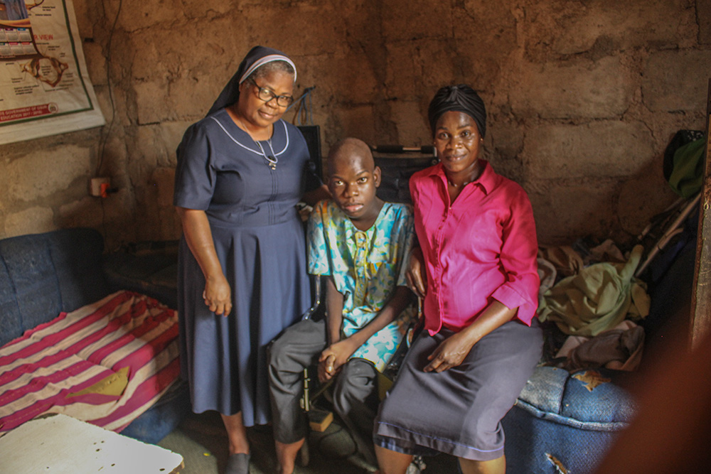 St. Louis Sr. Clara Azubuike (left) poses for a photo with Ogoluwa (center), who left school in grade 4 when he could no longer walk. His family had to move far from their town when they could no longer deal with the trauma of the stigma associated with his condition. (GSR photo/Valentine Benjamin)