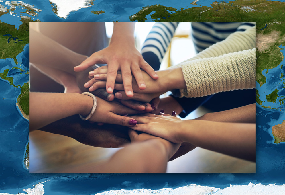 Hands joining in support overlaid on satellite image map of the Earth (Dreamstime/Yuri Arcurs/Scalinger)