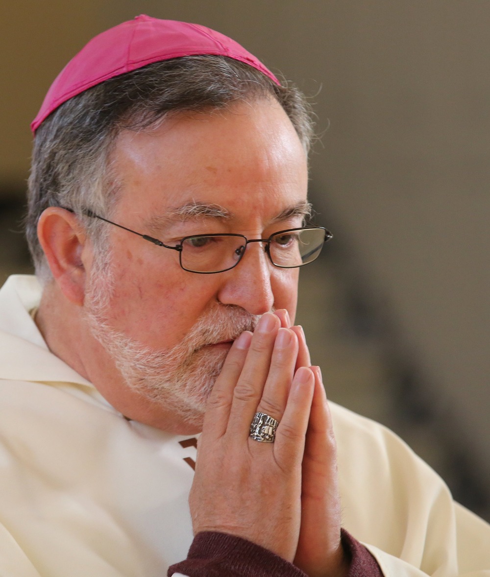 Prelate prays, vested