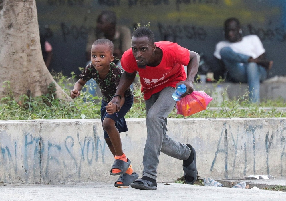 A man and young boy duck and run through street.