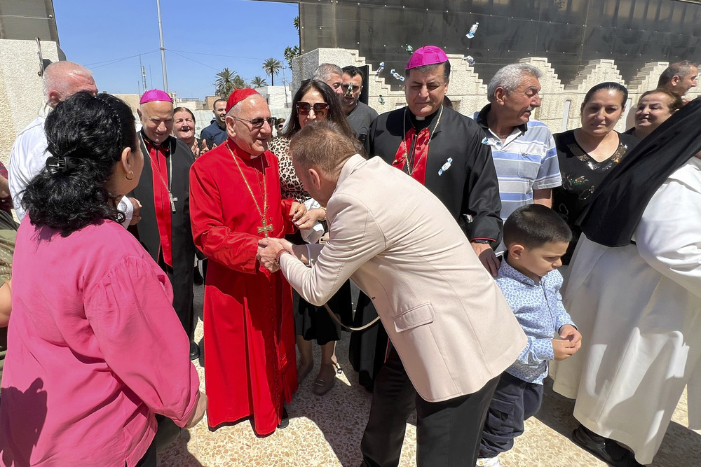 Chaldean patriarch, Iraq. Cardinal, wearing red clerical garb, greets joyful crowd in street.