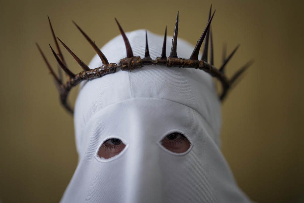 Spanish penitent Spanish member of penitential order wears hooded regalia and crown of thorns.