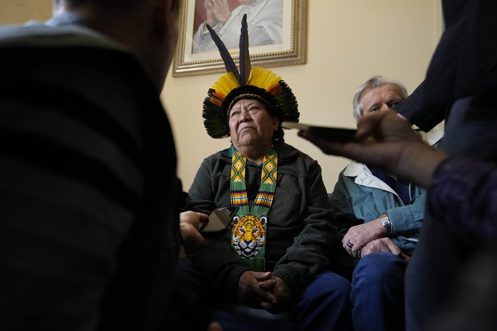 Yanomami leader, Pope Francis, Amazon repair. Man wearing traditional Amazonian garb sits while fielding questions