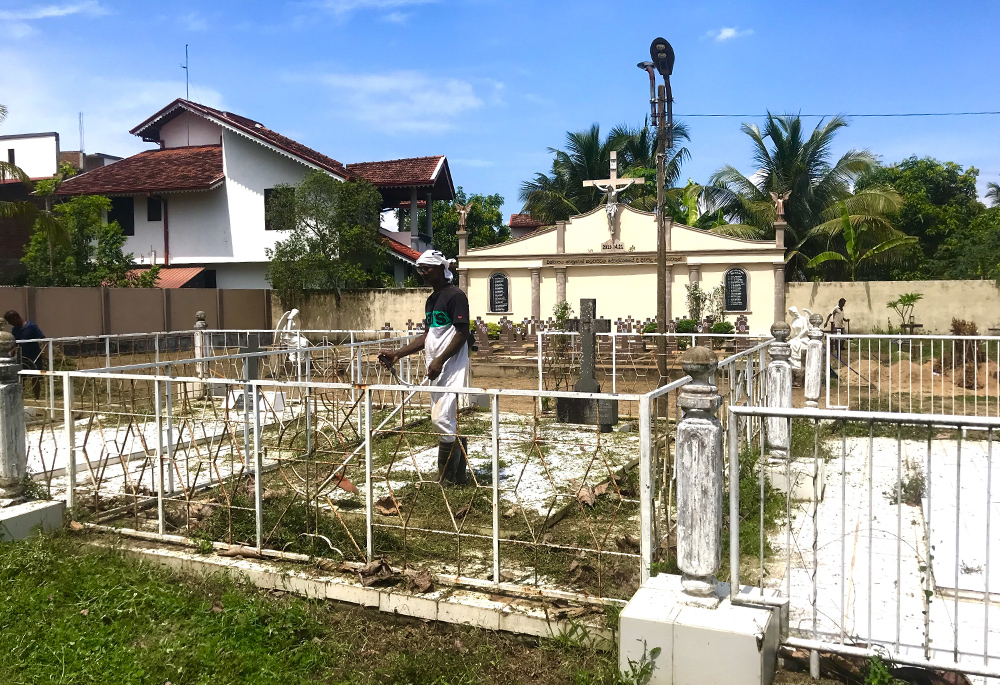 Raveen Peiris, whose daughter died in the 2019 Easter bomb attacks, cleans her tomb to prepare for the fifth memorial service. (Thomas Scaria)