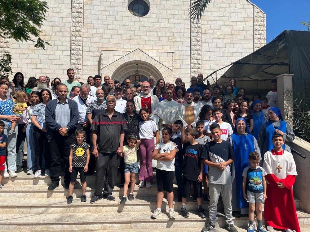 Cardinal, vested, stands on church steps, surrounded by faithful of Gaza.  