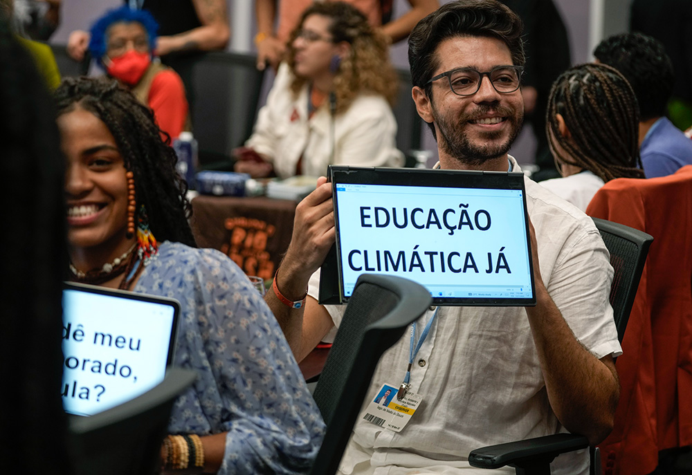 A man displays a sign in Portuguese that reads, "Climate education now," on Nov. 17, 2022, at the COP27 U.N. Climate Summit  in Sharm el-Sheikh, Egypt. (AP/Peter Dejong)