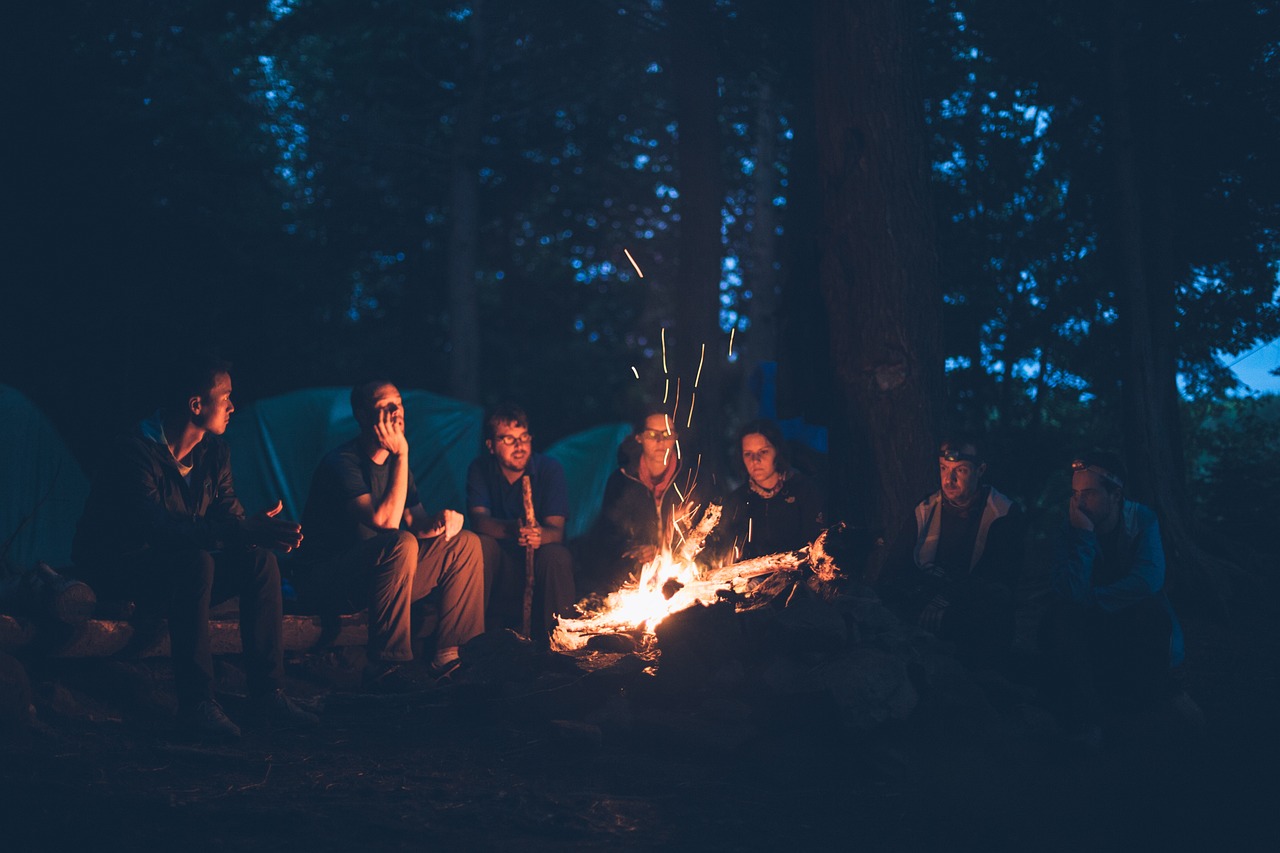 A group of young people sits around a campfire