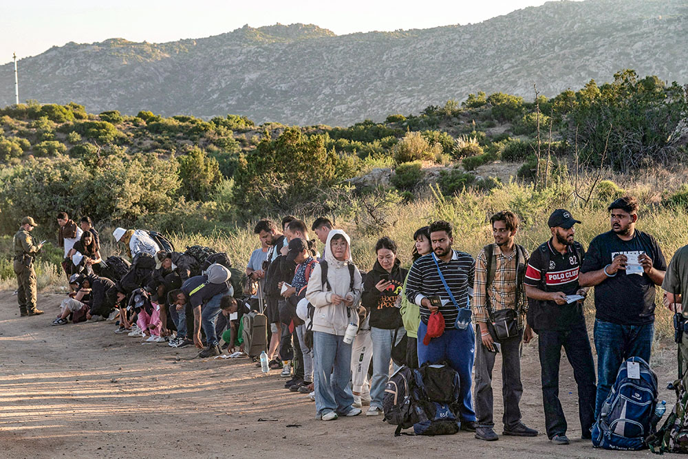 Asylum-seeking migrants stand in line to be transported at a staging area near the border wall in Jacumba Hot Springs, California, June 5, after U.S. President Joe Biden announced a sweeping border security enforcement effort. (OSV News/Reuters/Go Nakamura)