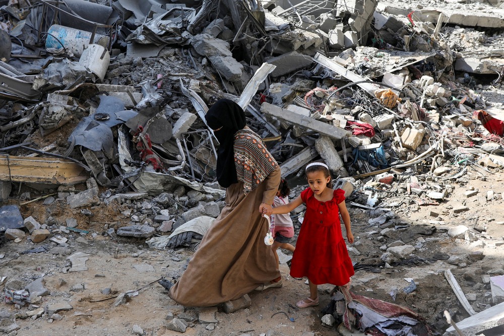 Woman and child step gingerly though rubble