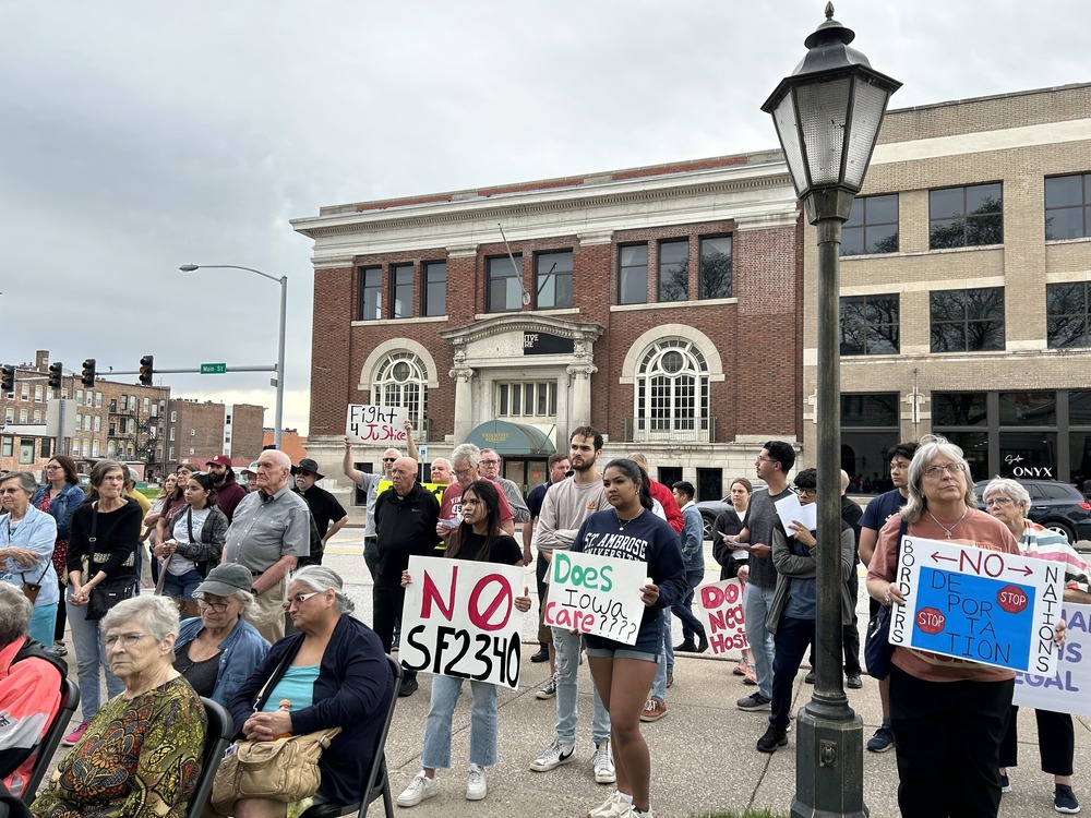 People stand on street holding signs in opposition to bill